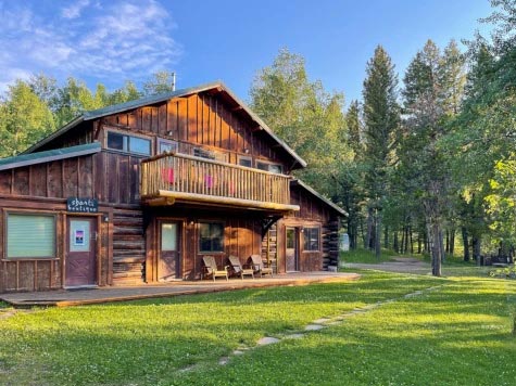 Cabin at Feathered Pipe Ranch in Montana amongst green grass and tall trees
