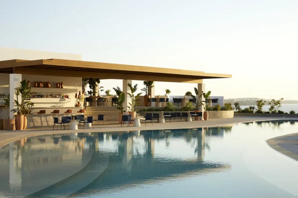 An infinity pool and poolside bar at a luxury resort with the backdrop of the Aegean Sea
