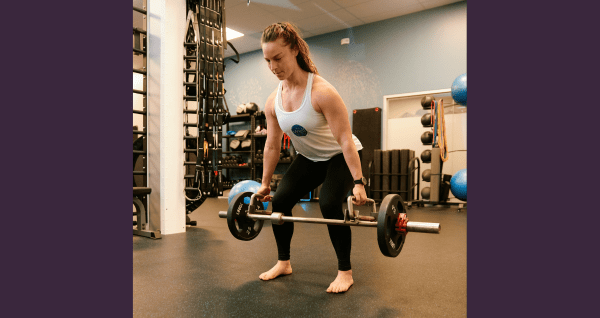 Well Studio Trainer Katie Dawson lifting weights to improve leg strength