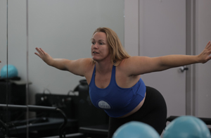 Pilates instructor with arms spread out in front of class.