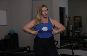 Pilates instructor with hands on side of body discussing abdomen strength.