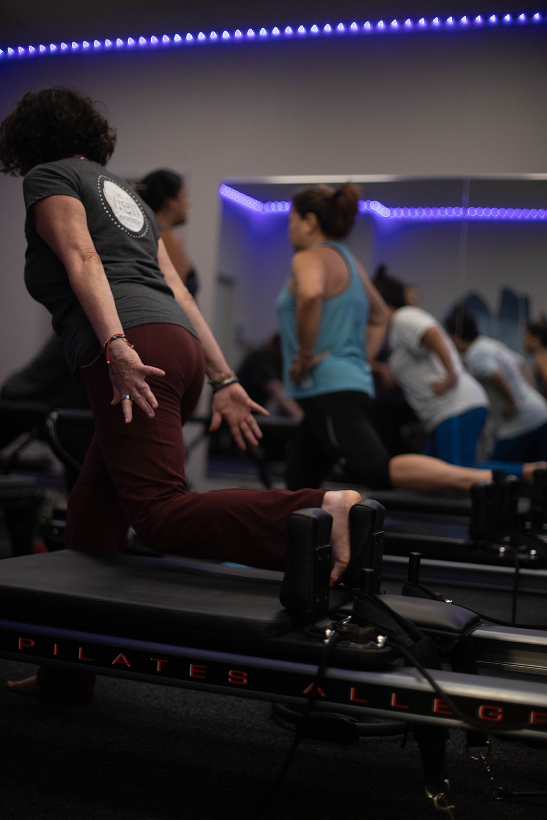 A group of women in a Pilates Reformer class working on flexibility.